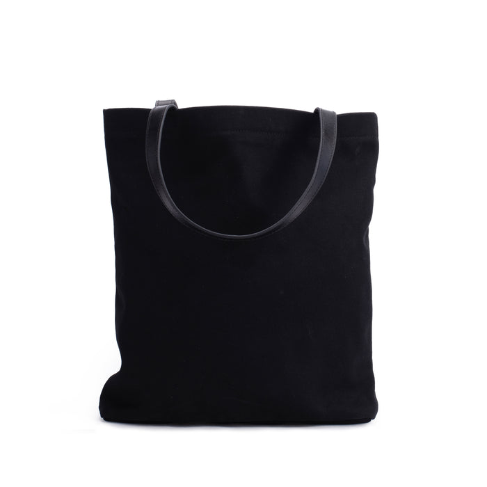 Black canvas tote bag with leather straps on white background