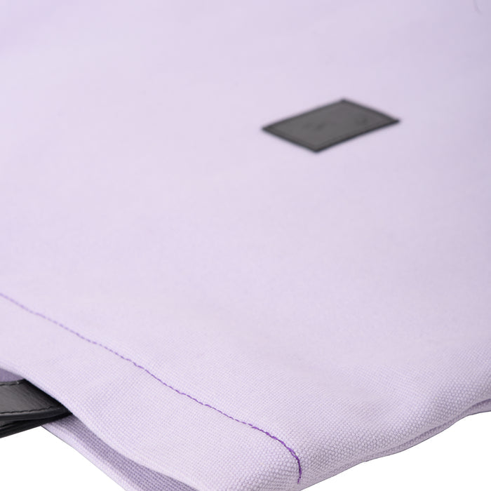 Close-up of a light purple fabric pouch with black tag and visible stitching