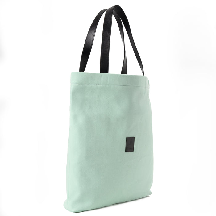Mint green canvas shoulder bag with black handles on white background