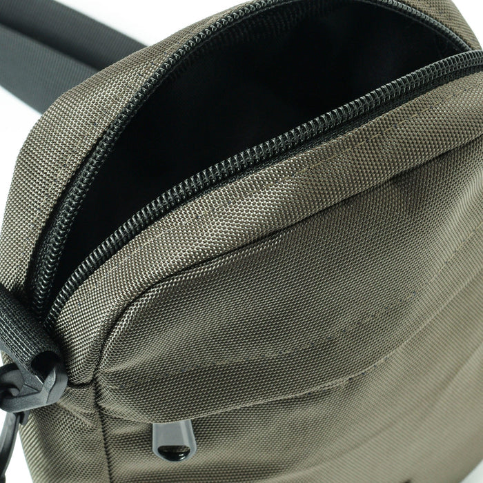 Close-up of a gray textured crossbody bag with black zipper and adjustable strap